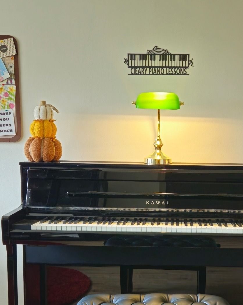 The teaching room: a black Kawai upright piano with a green banker's lamp and the Cleary Piano Lessons sign above it