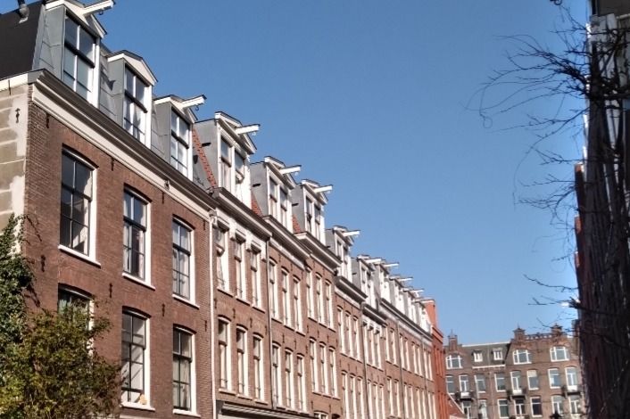 A terrace of brick houses with dormer windows on an Amsterdam street in Oud-West